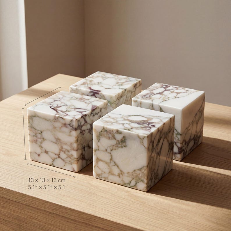 May include: Four marble cubes, each measuring 13 x 13 x 13 cm, are displayed on a wooden surface. The cubes have a white base with brown and purple veining, creating a natural, patterned design. The cubes are decorative.