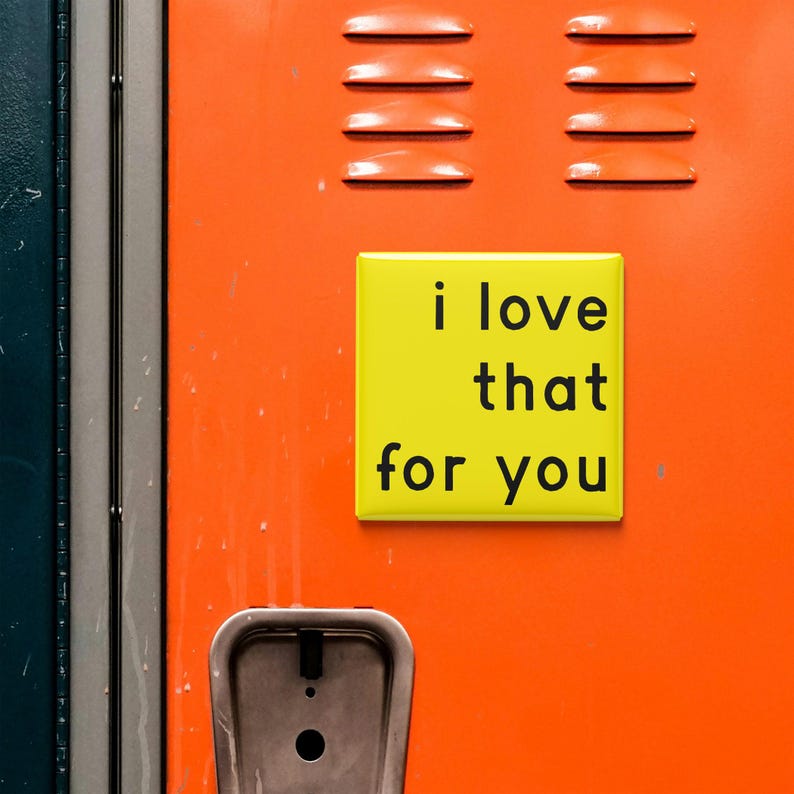 May include: A yellow square magnet with the phrase "i love that for you" in black text is affixed to an orange locker. The locker has ventilation slits and a silver handle. The background includes a section of a blue locker.