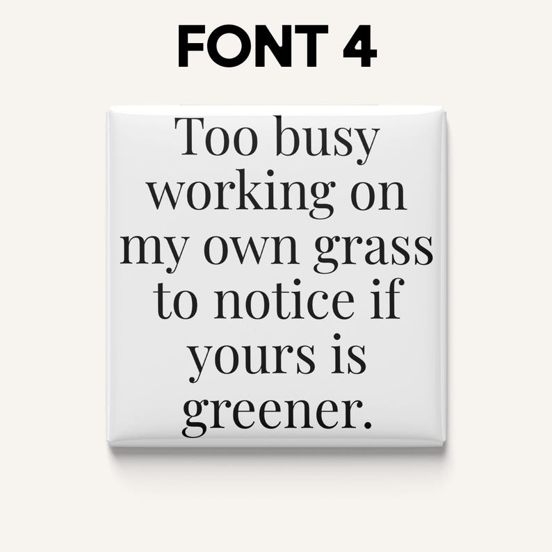 May include: A white square button with the text "Too busy working on my own grass to notice if yours is greener" in black font. The text "FONT 4" is at the top.