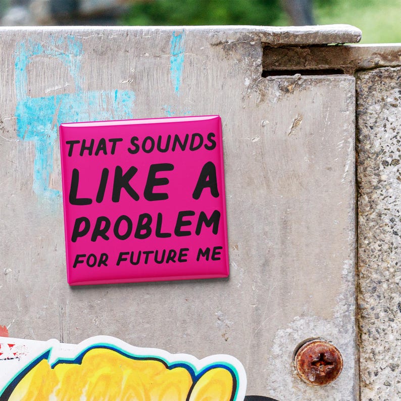 May include: A bright pink square button with the text "THAT SOUNDS LIKE A PROBLEM FOR FUTURE ME" in black. The button is affixed to a weathered, gray surface with other stickers and a rusty screw.