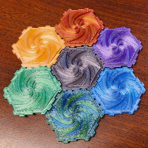 May include: Seven hexagonal coasters in a variety of colors, including orange, yellow, green, blue, purple, and gray. Each coaster features a swirling spiral design. The coasters are arranged on a wooden surface.