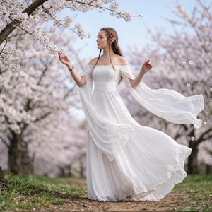 May include: A floor-length white off-the-shoulder dress featuring long, flowing, detached sleeves that drape from the upper arms. The garment has a fitted bodice with a defined waistline and a full, floor-length skirt made of lightweight fabric.