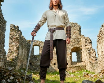Conjunto de ropa de caballero medieval con armadura: túnica con cordones, pantalón, cinturón celta y brazaletes de piel sintética para disfraz de feria renacentista.