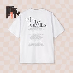Könnte beinhalten: Weißes T-Shirt mit einem schwarzen Grafikdruck, auf dem "enjoy the butterflies" steht und ein Gedicht über das Genießen der Momente des Lebens enthalten ist.