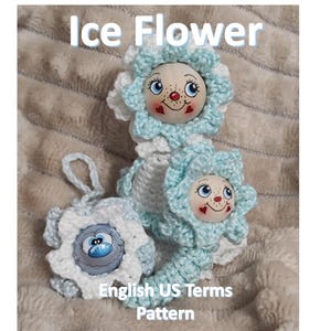Könnte beinhalten: Drei handgefertigte Häkelfiguren in Form von Blumen mit lächelnden Gesichtern und Herzakzenten. Die Blumen sind hellblau und weiß, mit dem Text "Ice Flower" und "English US Terms Pattern" sichtbar.