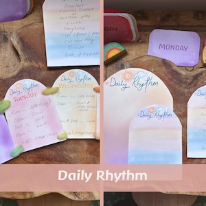 Op de afbeelding: Een verzameling kleurrijke Daily Rhythm notitieblokken met handgeschreven dagschema's. De notitieblokken hebben aquarel achtergronden en zijn gelabeld met dagen van de week. De afbeelding bevat een etui, houten figuren en decoratieve elementen.