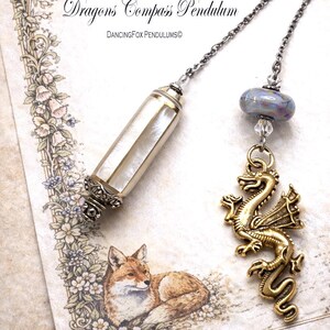 Könnte beinhalten: Pendel mit einer silbernen Kette und einem goldenen Drachenanhänger. Das Pendel hat einen klaren, rechteckigen Körper mit Perlmutt-Innenraum. Das Bild enthält den Text "Dragon's Compass Pendulum" und eine Fuchsgrafik.