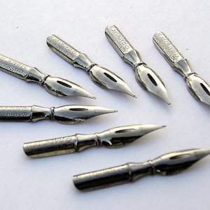May include: A set of six silver-toned calligraphy nibs with the text "COSTER DIAMOND" printed on each nib.