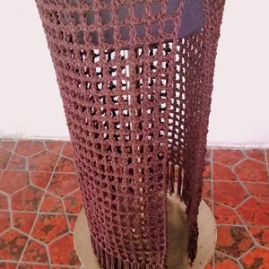 May include: A brown crocheted skirt with fringe on the bottom. The skirt is displayed on a mannequin and the text "Ms. Ann's Hands" is visible at the top of the skirt.