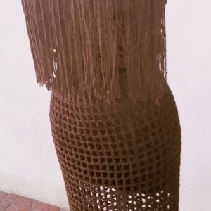 May include: A brown crochet dress with fringe detailing. The dress is on a mannequin and has a square neckline.