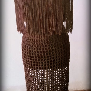 May include: A brown crochet dress with fringe detailing. The dress is on a mannequin and the text "Ms. Ann's Hands" is visible at the top of the image.