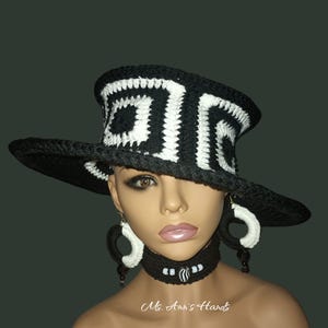 May include: A black and white crochet hat with a wide brim and geometric design. Matching earrings and a choker necklace with white beads complete the ensemble. The text "Ms. Ann's Hands" is visible.