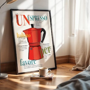 Könnte beinhalten: Ein gerahmtes Poster mit einer roten italienischen Espressomaschinen-Illustration. Das Poster enthält den Text "UN ESPRESSO" und "Italiano" in einem farbenfrohen Design. Eine Tasse Kaffee steht vor dem Poster auf einem Buch.