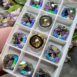 May include: A white plastic tray with 10 compartments, each containing a square iridescent gemstone. Two compartments contain gold-colored metal settings.