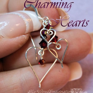 May include: Silver earrings with two dangling hearts and red crystal accents. The earrings are called "Charming Hearts".