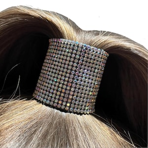 May include: A black hair tie with iridescent rhinestones covering the entire surface.