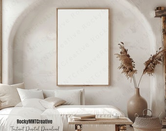 May include: A white couch with pillows and a wooden coffee table with books on it. A vase with dried pampas grass sits on the floor next to a woven basket. The room has a white wall with a large framed picture.