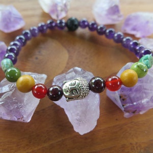 Puede incluir: Un brazalete de chakras con un dije de Buda plateado, con cuentas de amatista, verde, amarillo, rojo y granate.