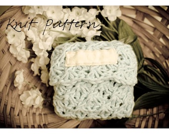 May include: A light blue knitted pouch with a white label that says "Knit Pattern" in a wicker basket with white flowers.
