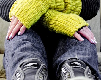 May include: A person wearing a black sweater with yellow knitted arm warmers and blue jeans. The person is wearing black shoes.
