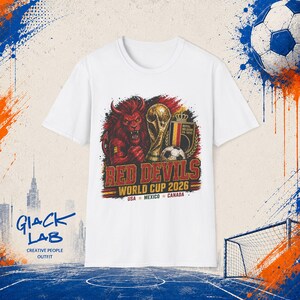 Può includere: Una t-shirt bianca con la grafica di un leone rosso, un trofeo dorato, un pallone da calcio e uno scudo con il testo Royal Belgian FA 1895. Sotto, il testo recita RED DEVILS WORLD CUP 2026 USA MEXICO CANADA in lettere rosse e gialle.