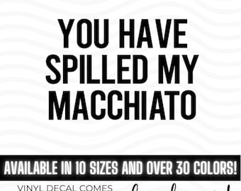 May include: A black vinyl decal featuring the text YOU HAVE SPILLED MY MACCHIATO in a bold, sans-serif font. The design is presented against a white background with wavy lines, accompanied by text indicating availability in 10 sizes and 30 colors.