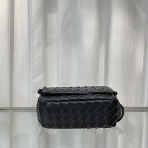 Op de afbeelding: Zwarte crossbodytas van leer met een geweven patroon. De tas heeft een rechthoekige vorm en een klepsluiting. Het geweven patroon bedekt de hele tas en heeft een dunne, verstelbare riem. Ongeveer 20 cm lang.