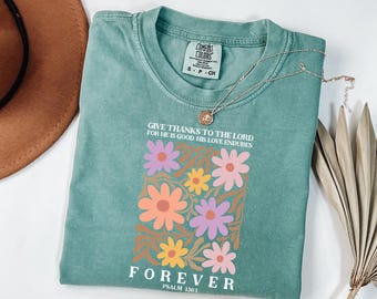 May include: A teal blue t-shirt with a floral design and the text "Give thanks to the Lord for he is good. His love endures forever. Psalm 136:1".