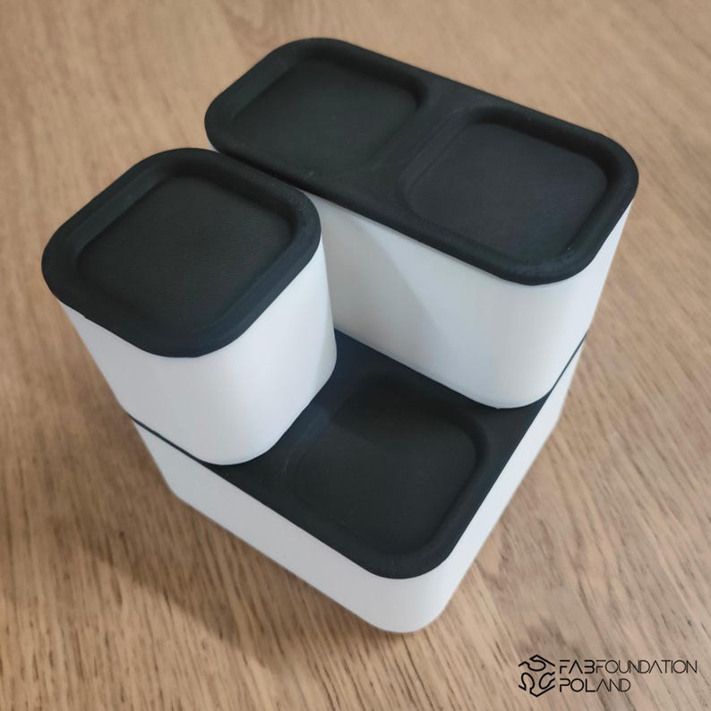Pu&ograve; includere: Un contenitore bianco e nero con un design geometrico unico. Il contenitore ha tre sezioni, ciascuna con un coperchio nero. Il design &egrave; moderno e minimalista, adatto per organizzare piccoli oggetti.