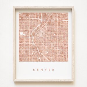 Könnte beinhalten: Ein gerahmter Druck einer Karte von Denver, Colorado. Die Karte ist in einem hellbraunen Farbton mit weißen Linien, die die Straßen zeigen. Das Wort "DENVER" ist unten auf der Karte in Weiß gedruckt.