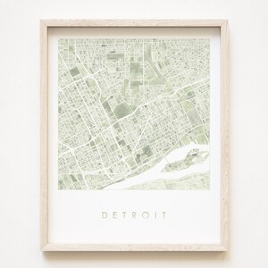Könnte beinhalten: Ein gerahmter Druck einer grünen und weißen Aquarellkarte von Detroit, Michigan. Die Karte ist von einem hellen Holzrahmen umgeben und der Name der Stadt ist in Grün unter der Karte gedruckt.