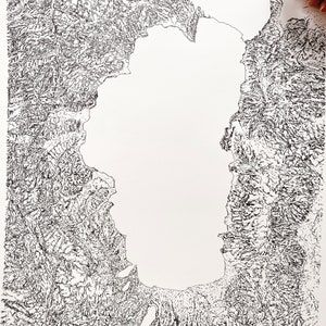 Op de afbeelding: Gedetailleerde zwart-wit topografische kaartillustratie. De kaart toont een groot waterlichaam omgeven door getextureerd land, met fijne lijnen die diepte en hoogte cre&euml;ren. Een hand tekent met een pen op de kaart.