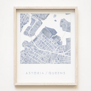 May include: A framed watercolor print of a map of Astoria, Queens, New York City. The map is in shades of blue and white, with the text "ASTORIA / QUEENS" at the bottom.
