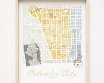 May include: A watercolor map print of Columbia City, Seattle, in shades of yellow, gray, and green. The map is framed in a light wood frame. The text "Columbia City Seattle" is printed below the map.