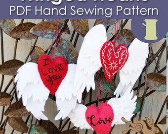 May include: Three felt winged hearts with different embroidery designs. The hearts are red and the wings are white. The hearts are hanging from a rusty metal background. The text on the hearts reads "I Love You" and "Love".