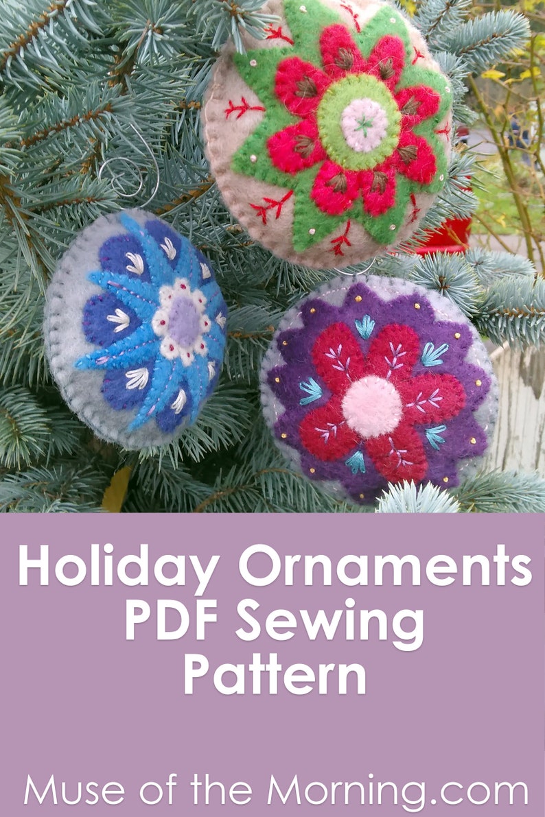 May include: Three felt Christmas ornaments with embroidered flower designs. The ornaments are red, blue, and purple with white and green accents. The ornaments are hanging on a green pine tree branch. Holiday Ornaments PDF Sewing Pattern Muse of the Morning.com