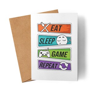 Könnte beinhalten: Eine weiße Grußkarte mit den Worten "EAT SLEEP GAME REPEAT" in farbigen rechteckigen Kästchen. Die Karte wird von einem braunen Umschlag begleitet. Der Text wird von einer Gabel, einem schlafenden Gesicht, einem Gamecontroller und einem Kreispfeil begleitet.