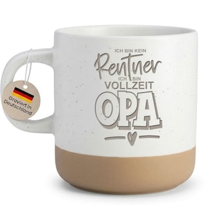 Könnte beinhalten: Weißer Keramikbecher mit gesprenkelter Oberfläche und beigefarbenem Boden. Der Becher trägt den deutschen Text "ICH BIN KEIN Rentner ICH BIN VOLLZEIT OPA" und ein Etikett mit der deutschen Flagge und dem Text "Graviert in Deutschland".