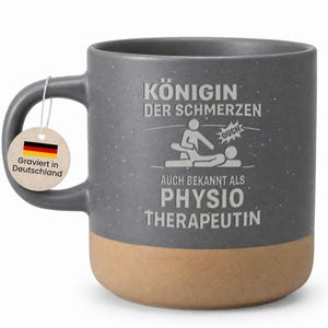 Könnte beinhalten: Graue Keramiktasse mit beigefarbenem Boden, mit deutschem Text und einer Grafik einer Person, die Physiotherapie erhält. Die Tasse hat einen Henkel und ein Etikett "Graviert in Deutschland".