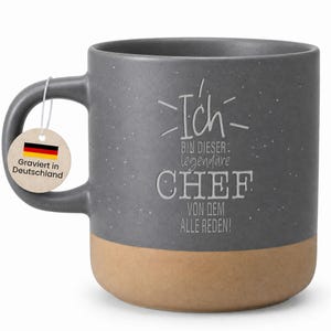 Könnte beinhalten: Graue Keramiktasse mit gesprenkelter Oberfläche und beigefarbenem Boden. Die Tasse trägt den deutschen Text "Ich bin dieser legendäre CHEF von dem alle reden!" und ein Etikett "Graviert in Deutschland".