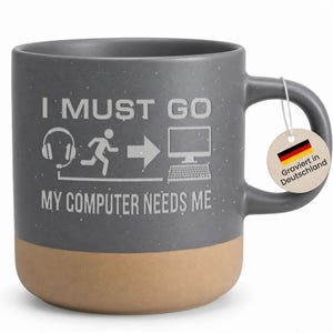 Könnte beinhalten: Graue Keramiktasse mit gesprenkelter Oberfläche und beigem Boden. Auf der Tasse steht der Text "I MUST GO" über einer Grafik einer Person, die auf einen Computer zuläuft, mit dem Text "MY COMPUTER NEEDS ME" darunter. Ein Etikett lautet "Graviert in Deutschland".