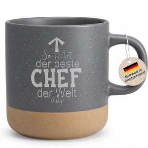 Könnte beinhalten: Graue Keramiktasse mit gesprenkelter Oberfläche und beigefarbenem Boden. Die Tasse hat weißen Text mit der Aufschrift "So sieht der beste CHEF der Welt aus" und ein Etikett mit der deutschen Flagge.