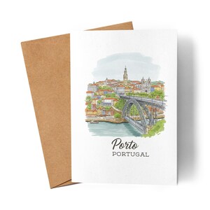 Könnte beinhalten: Eine weiße Grußkarte mit einer Aquarellillustration von Porto, Portugal, mit einer Brücke, Gebäuden und dem Text "Porto Portugal". Die Karte wird von einem braunen Umschlag begleitet.