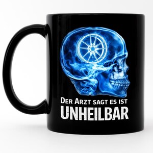 Könnte beinhalten: Schwarze Keramik-Tasse mit einem blauen, leuchtenden Schädel und einem Autoreifen-Design. Der Text "Der Arzt sagt es ist UNHEILBAR" ist darunter in Weiß gedruckt.