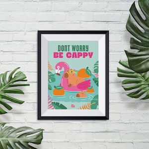Puede incluir: Un p&oacute;ster enmarcado con un fondo azul claro que presenta un capibara de dibujos animados con gafas de sol flotando en un flotador de piscina rosa en forma de flamenco. El texto "Don't Worry Be Cappy" est&aacute; escrito en letras negras sobre el capibara. El p&oacute;ster est&aacute; rodeado por un marco negro.