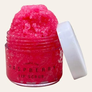 Könnte beinhalten: Ein rosa Lippenpeeling in einem durchsichtigen Glas mit weißem Deckel. Das Glas ist mit "LashLix Raspberry Lip Scrub" beschriftet.