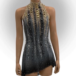 Puede incluir: Maillot de cuello halter con un diseño degradado, que va del negro al gris. El corpiño y el escote están adornados con pedrería dorada y plateada. La falda tiene un dobladillo asimétrico, creando una silueta dinámica.