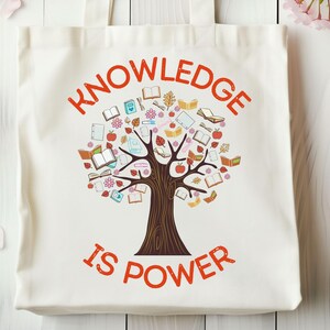 May include: A white tote bag with orange handles features a graphic of a tree made of books and the text "KNOWLEDGE IS POWER".