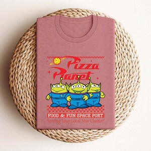 a pink t - shirt with a cartoon character on it