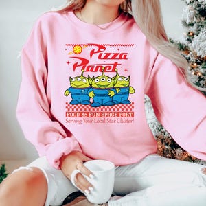 a woman in a pink sweatshirt is holding a coffee mug